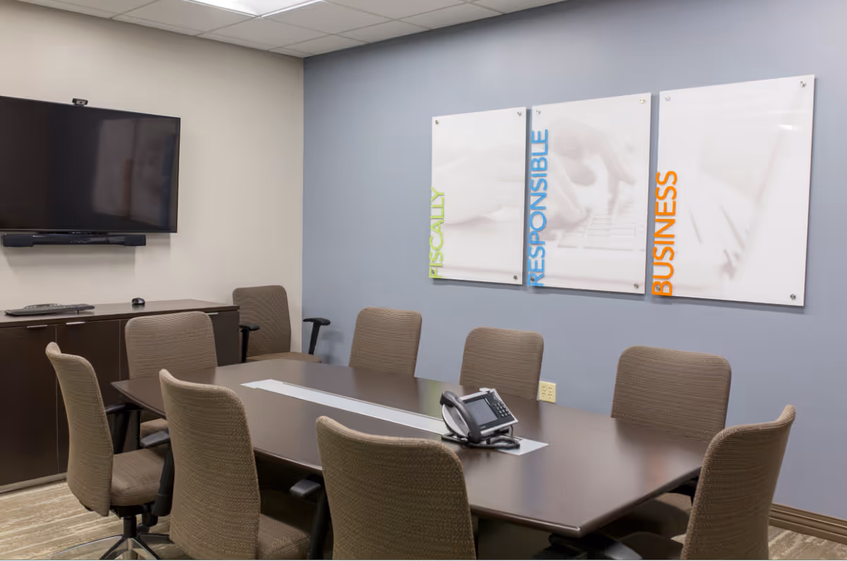 Conference room with a long table, chairs, wall TV, and three motivational panels.