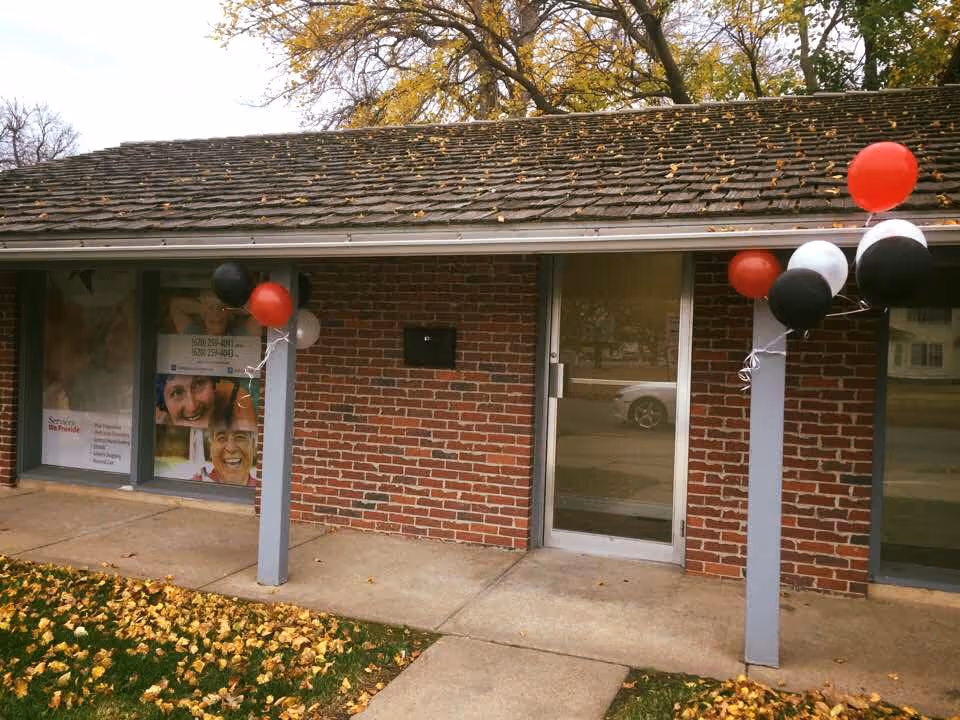 Brick senior care facility entrance with balloons; autumn leaves on the walkway.