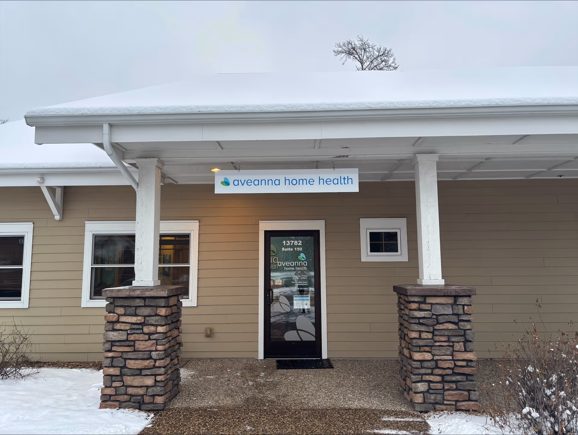 Front entrance of Aveanna Home Health building with snow and sign.