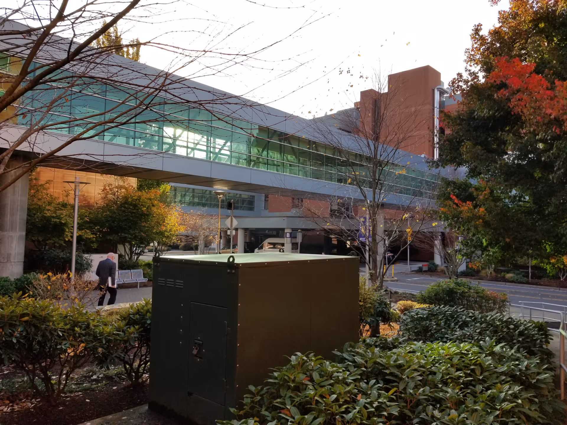 Exterior view of Salem Health Emergency Department with glass walkway, trees, and a large utility box.