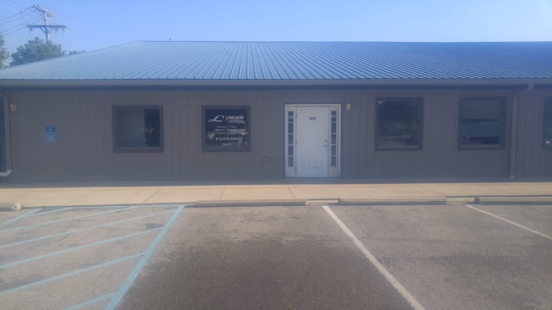 Single-story gray facility with metal blue roof, front entrance, and Lincare sign.