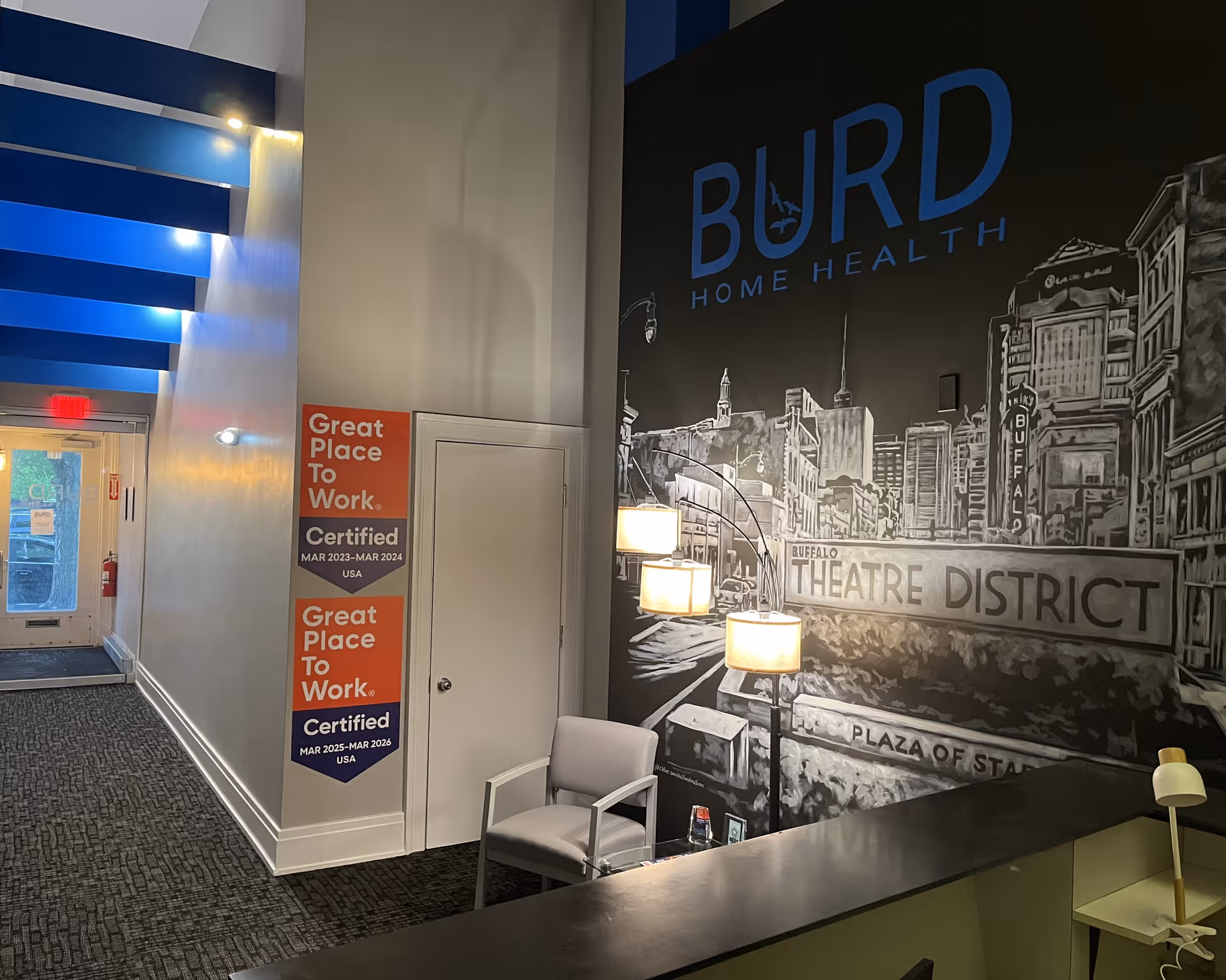 Indoor hallway featuring BURD mural, seating area, and Great Place To Work posters