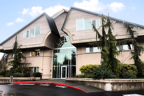 Brick senior living facility with an arched glass entrance and manicured landscaping.