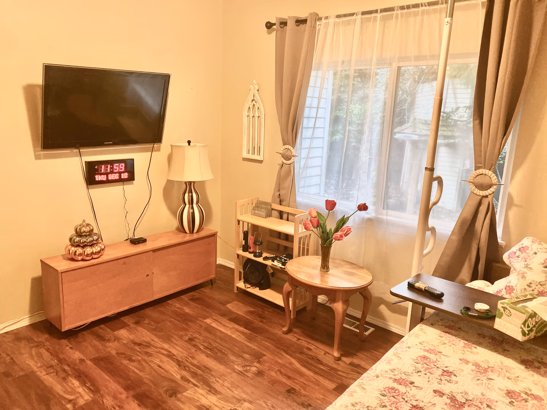 Living room in Harmony Place Adult Family Home with TV, tulip bouquet, and large window.