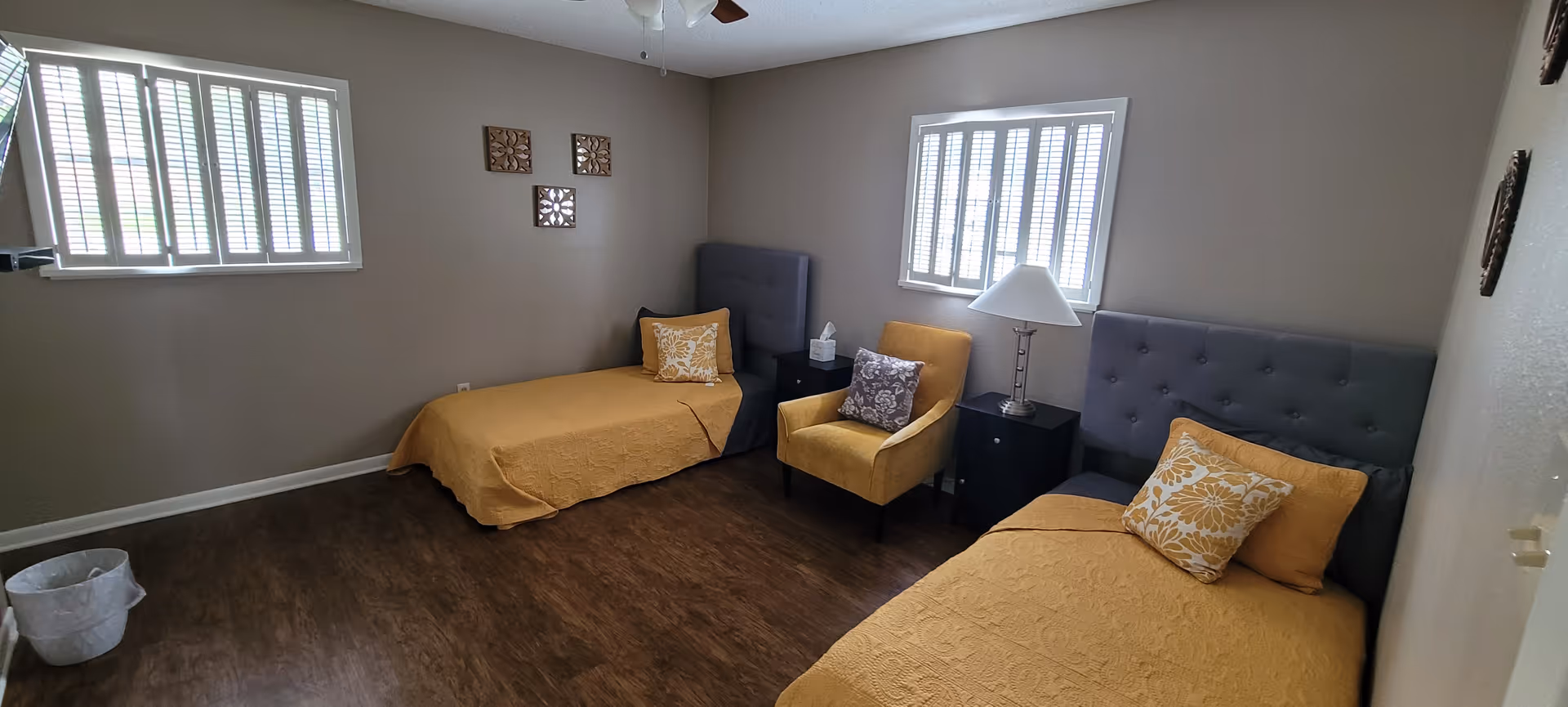 Two twin beds in a shared bedroom with yellow bedding, chairs, and nightstands.