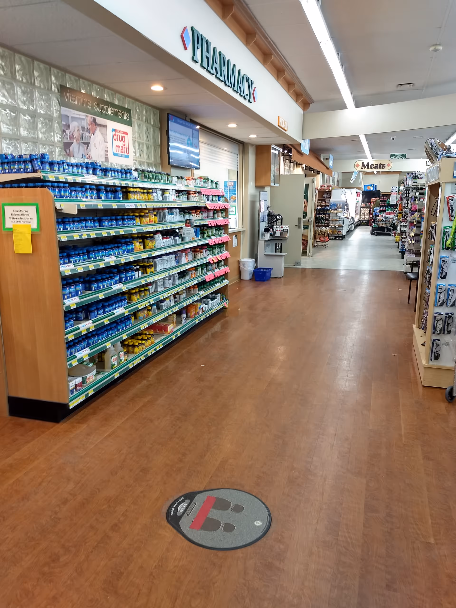 Inside a Discount Drug Mart store with shelves of medications and a pharmacy sign.