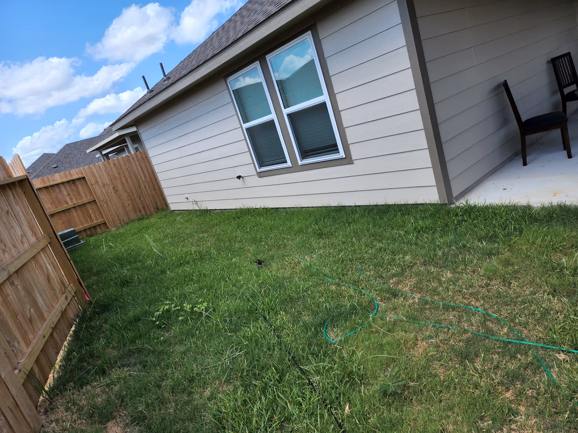 Exterior view of a house with a grassy backyard and a small covered patio.