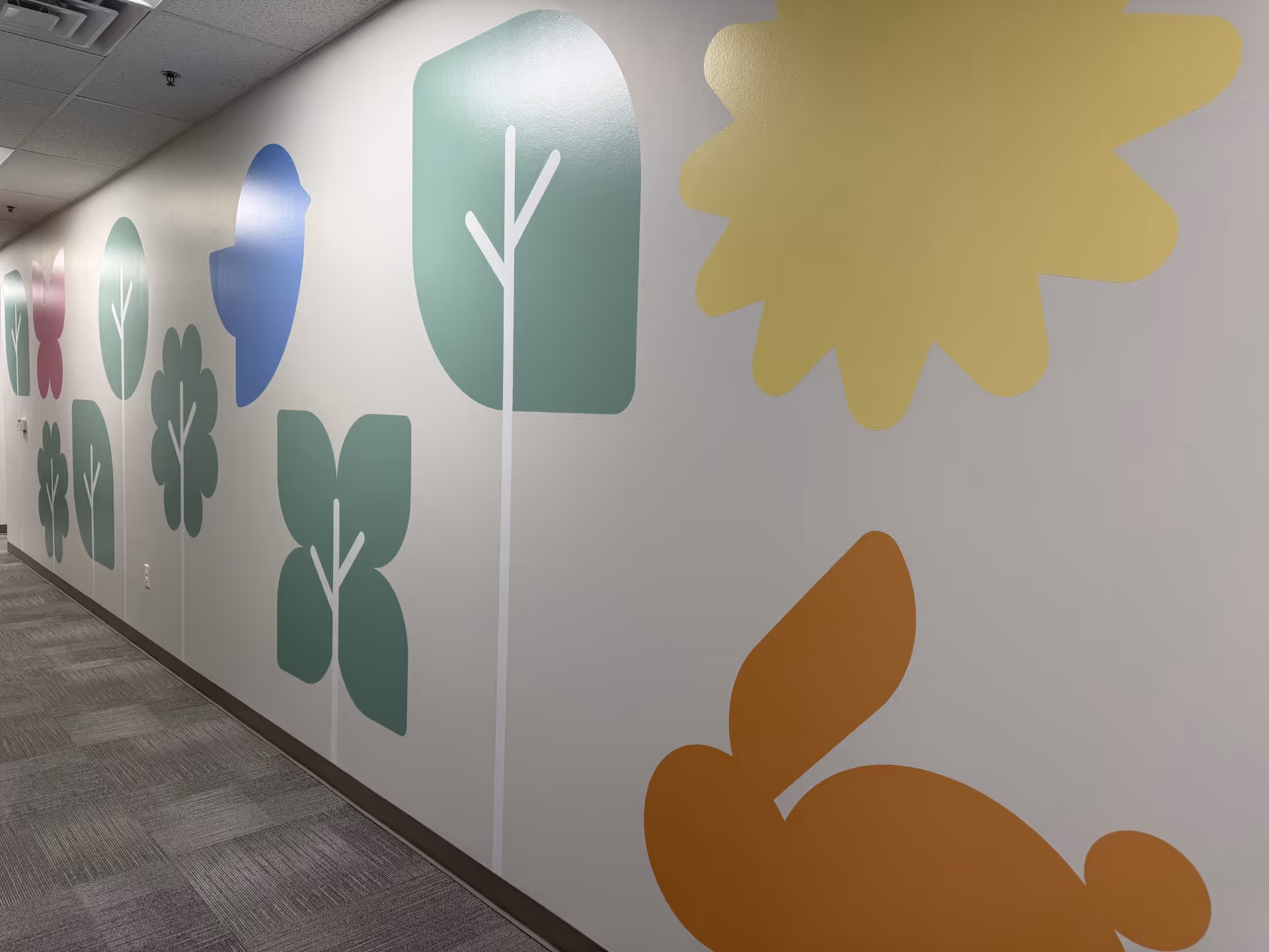 Interior hallway of a senior living facility with colorful wall decor shapes.