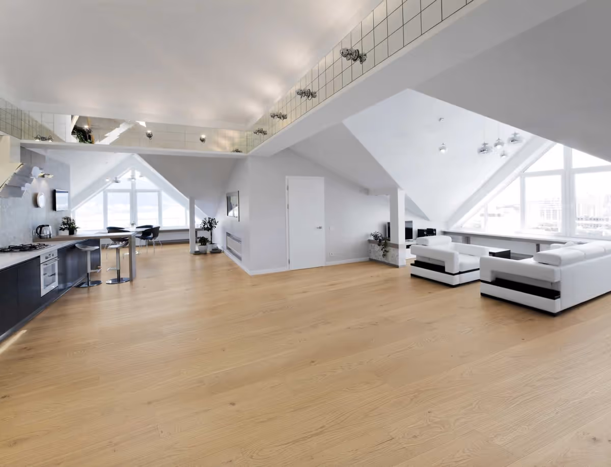 Bright open-concept senior living lounge with white sofas, a kitchenette, and large windows.