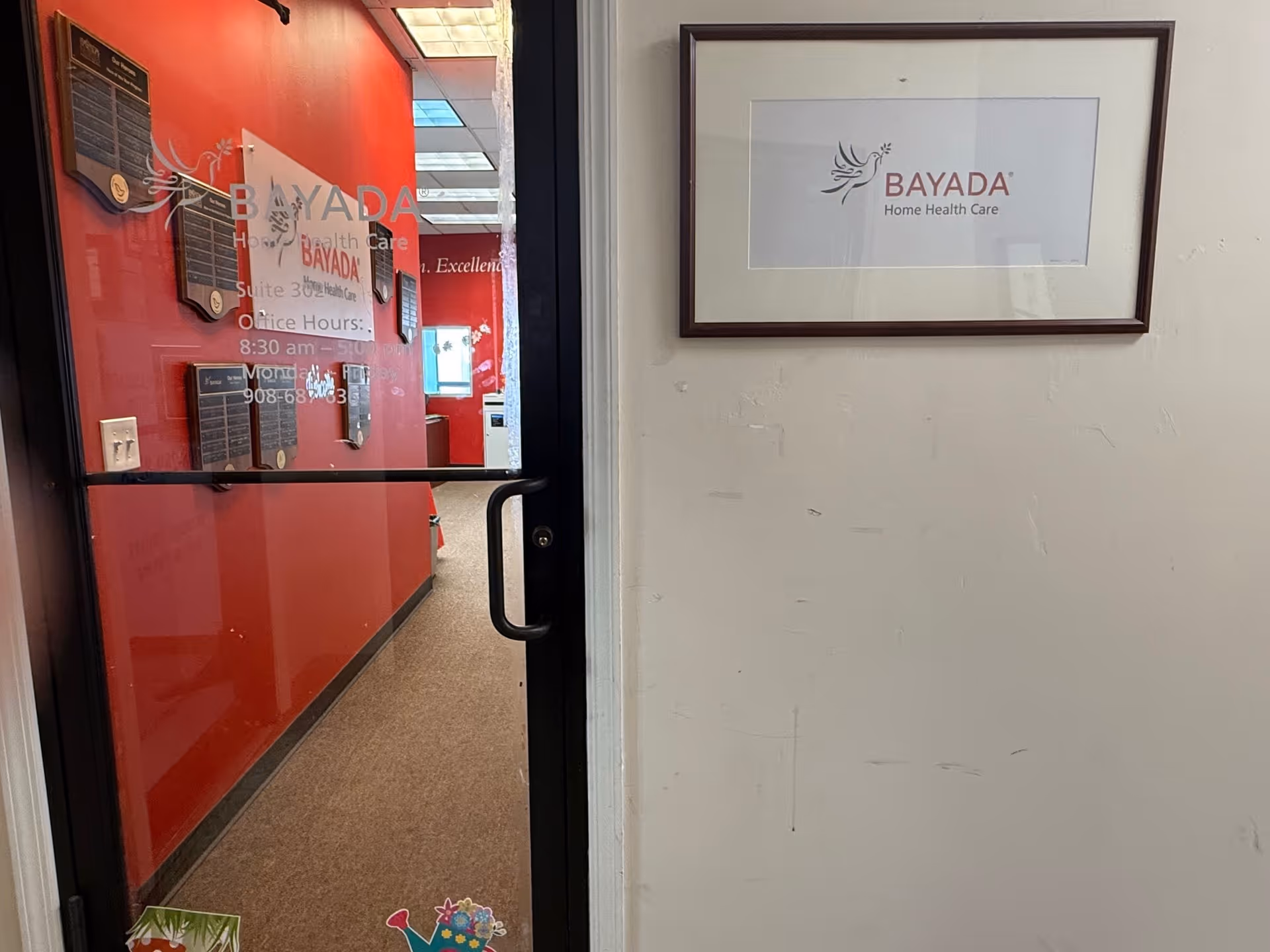 Interior hallway with glass door, red wall, and BAYADA signage.