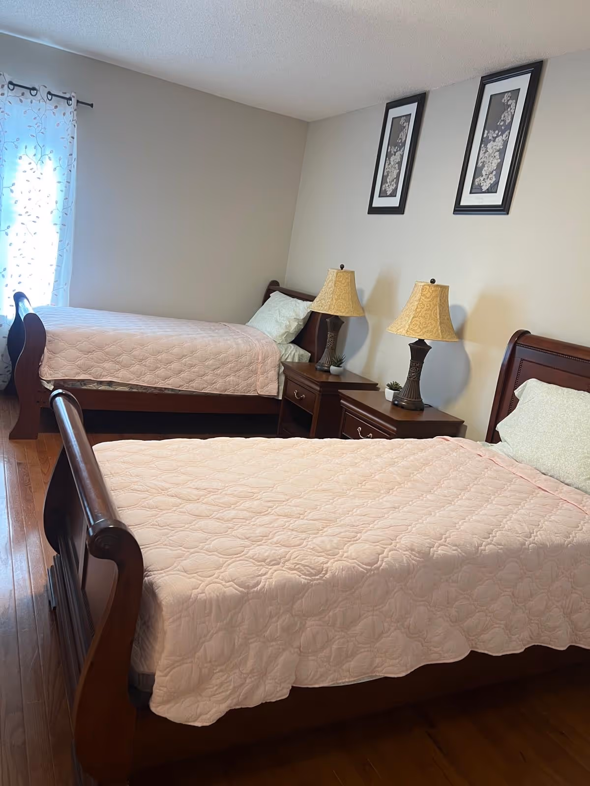 Two wooden beds with pink quilts in a tidy shared bedroom.
