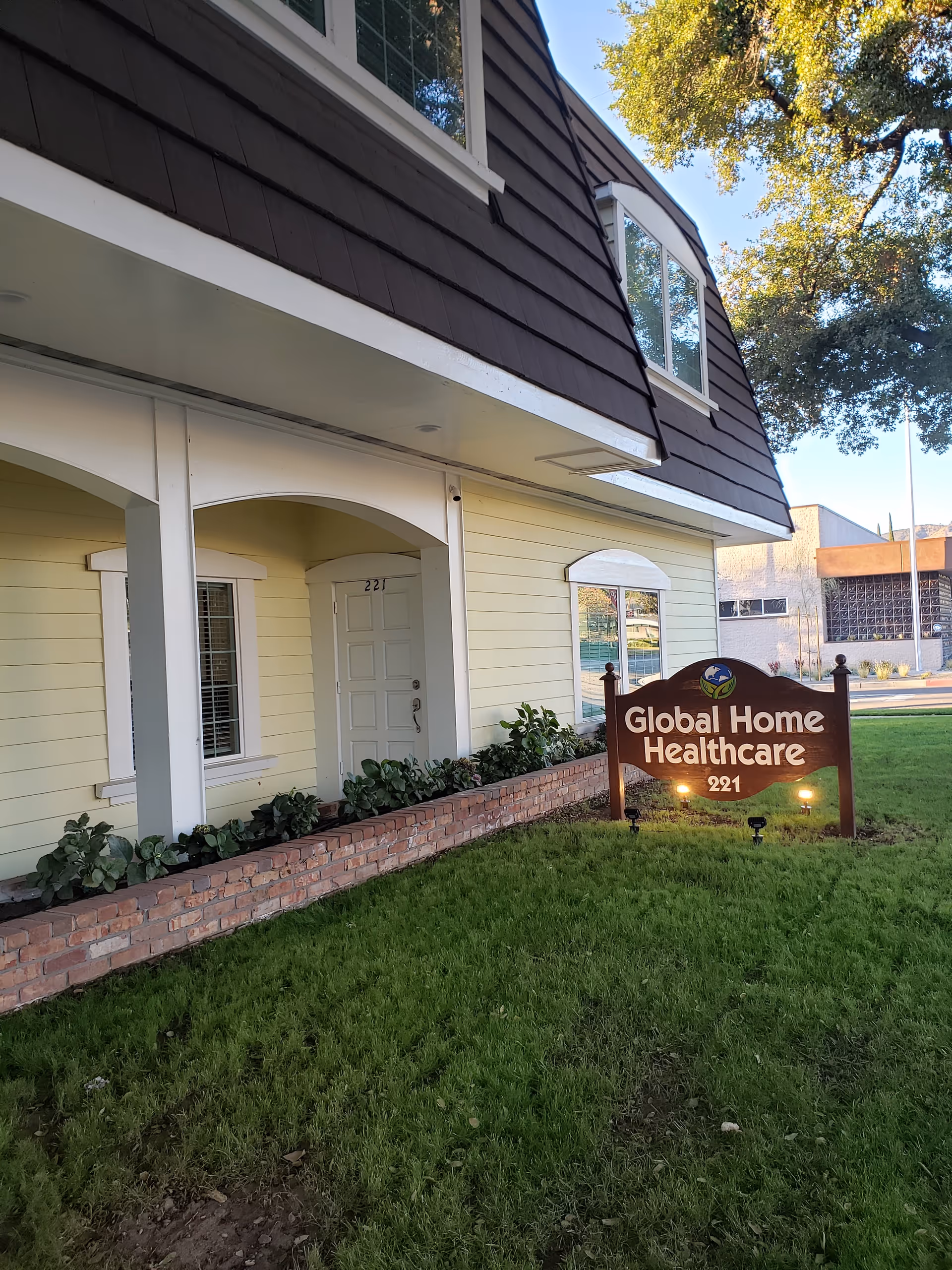 Front exterior of a yellow building with a Global Home Healthcare sign and green lawn.
