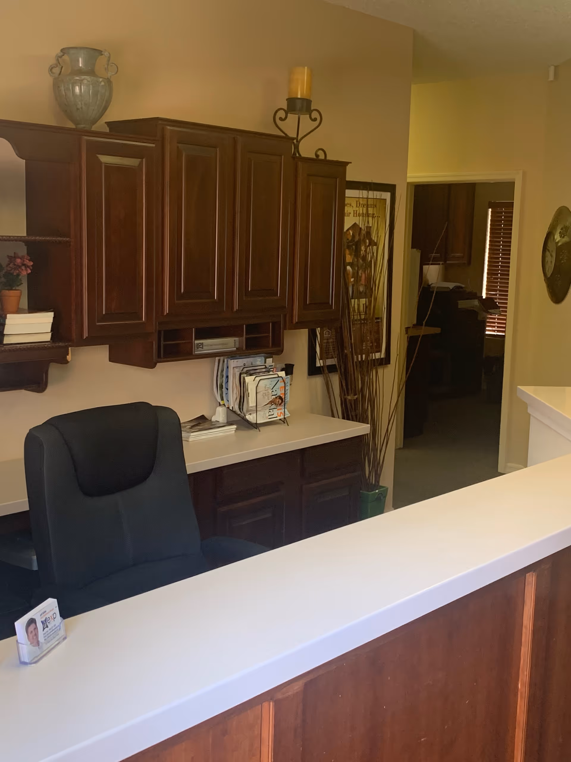 Reception desk with dark wood cabinets, chair, and decor in a senior care lobby.