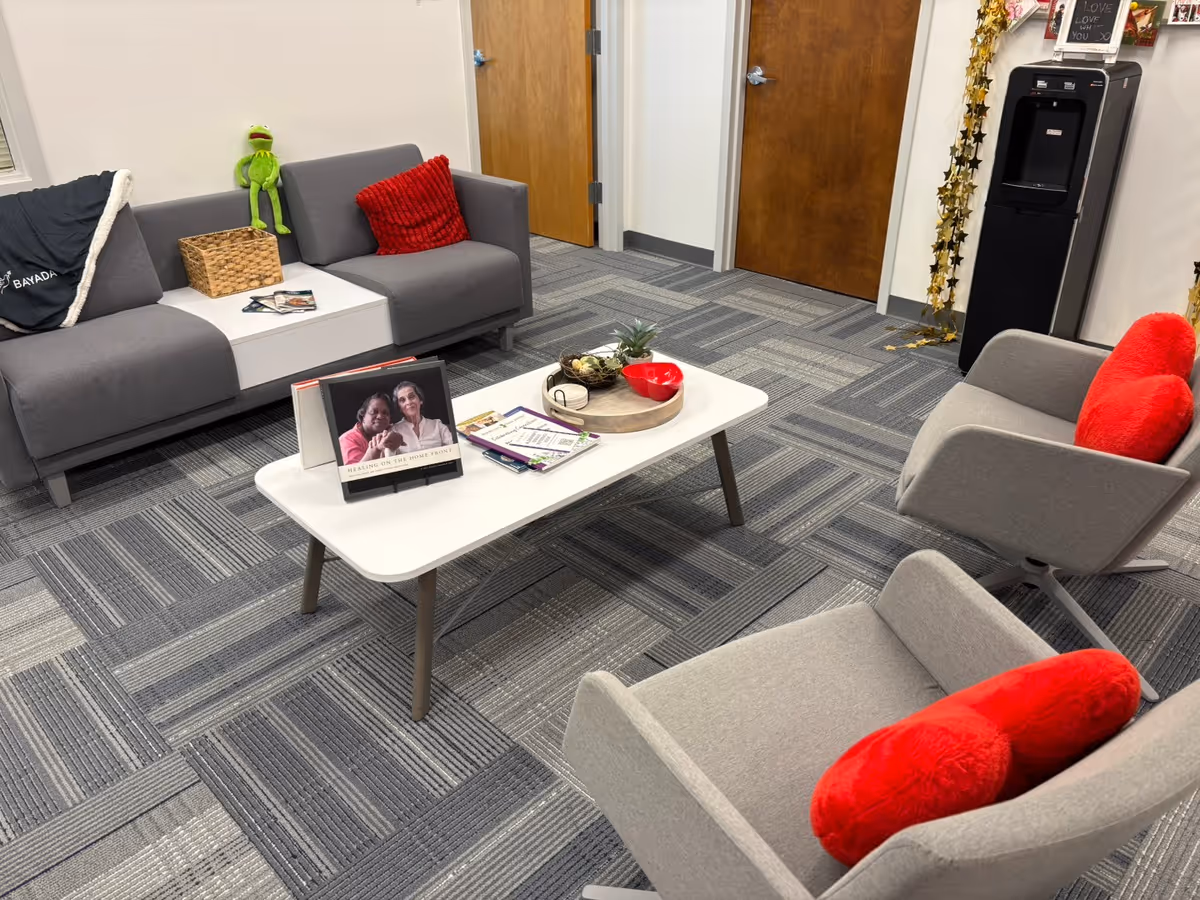 Modern lounge with gray seating, red cushions, and a white coffee table.