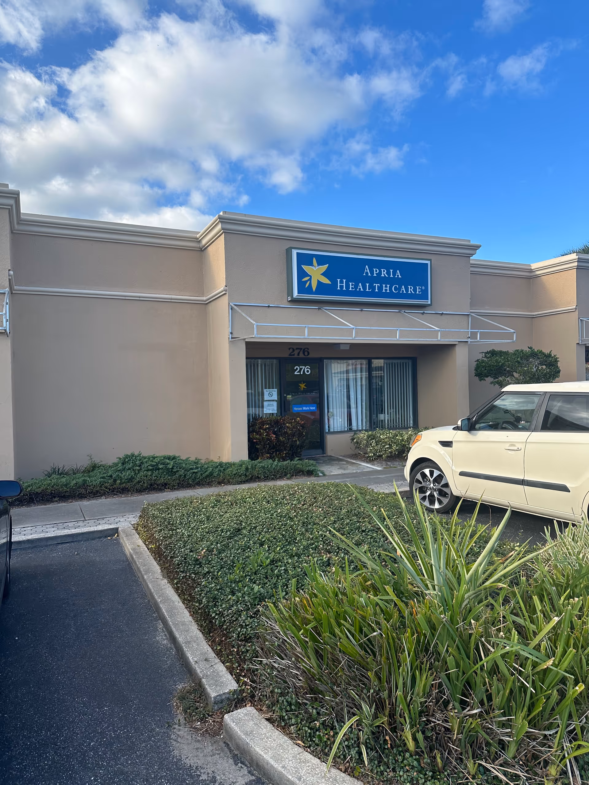 Exterior view of an Apria Healthcare building with parking lot and landscaping.