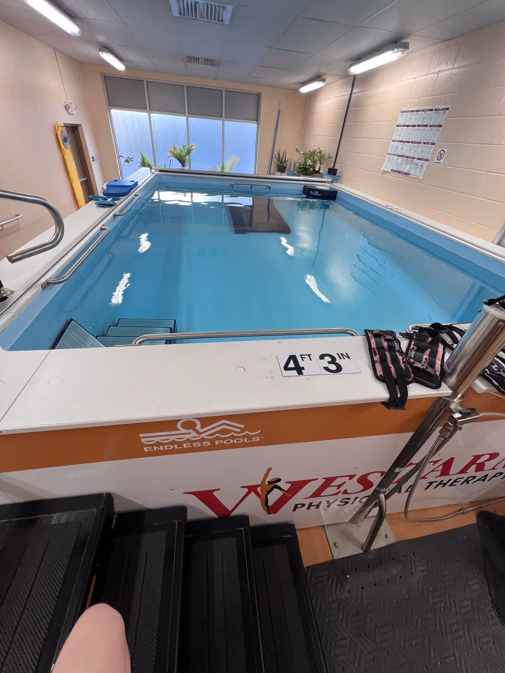 Indoor therapy pool with steps and rails in a rehabilitation facility.