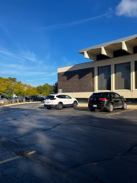 Exterior view of a brick facility with parked cars in front.