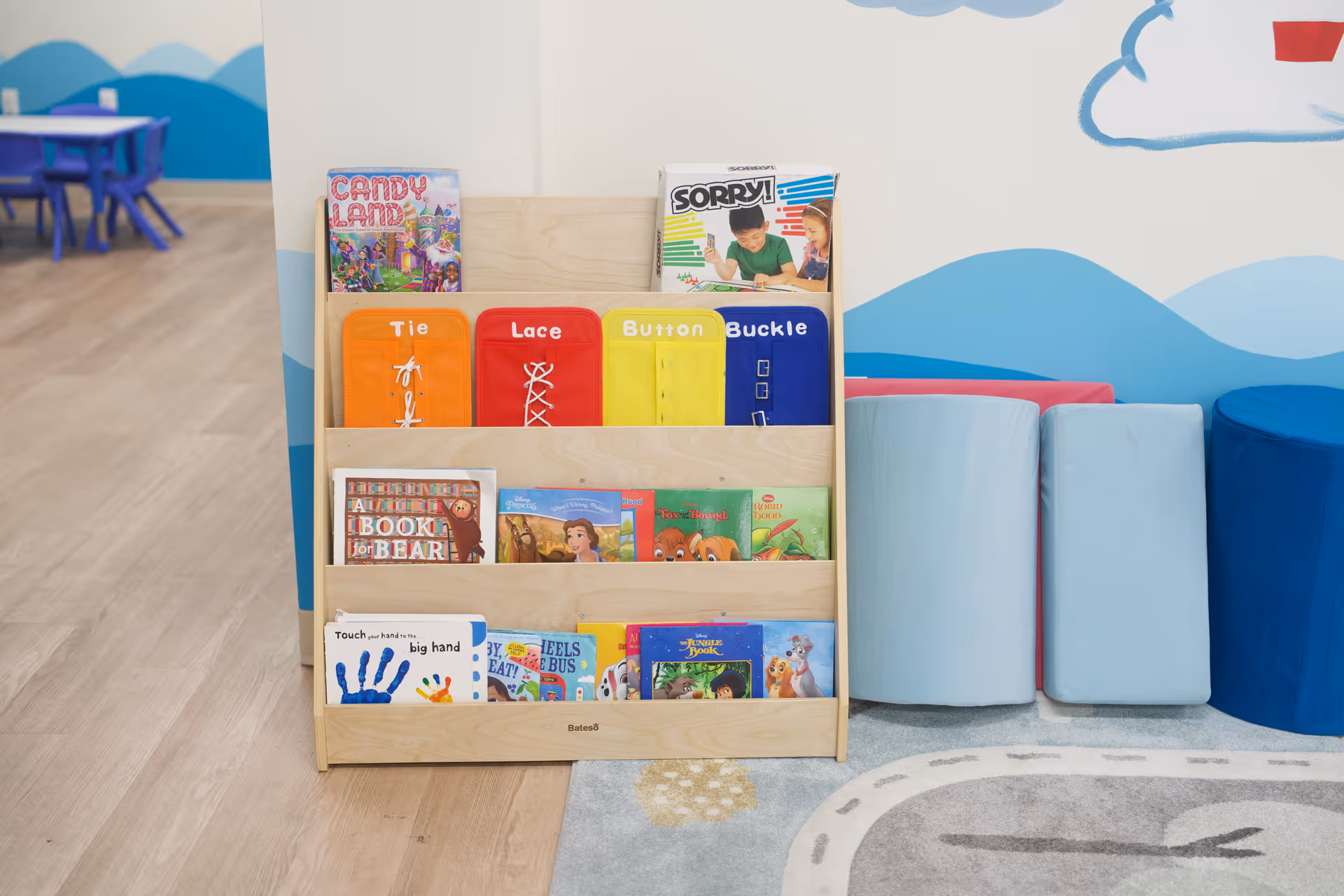 Colorful children's book shelf and soft seating in a bright therapy room.