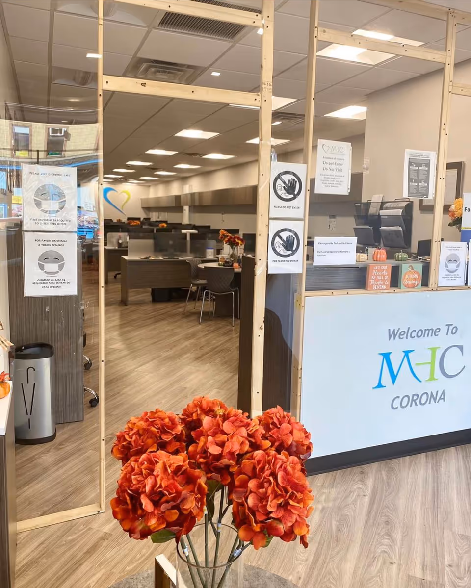 Lobby area of Marks Home Care Agency Corona with reception desk, posters, and orange flowers.