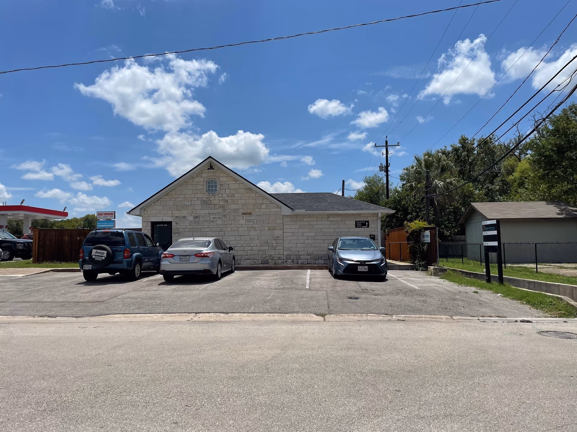 Stone building with parked cars in front under a bright blue sky.