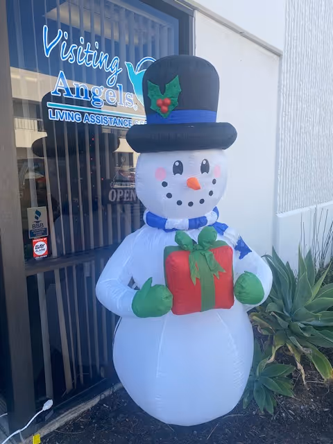 An inflatable snowman decoration stands outside the Visiting Angels entrance.