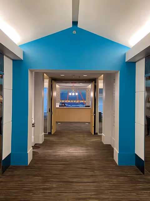 Blue accented hallway leading to a reception desk in a modern senior living facility.