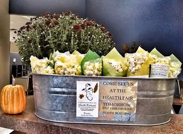 Galvanized tub with flowers and a pumpkin beside a health fair sign on a counter.