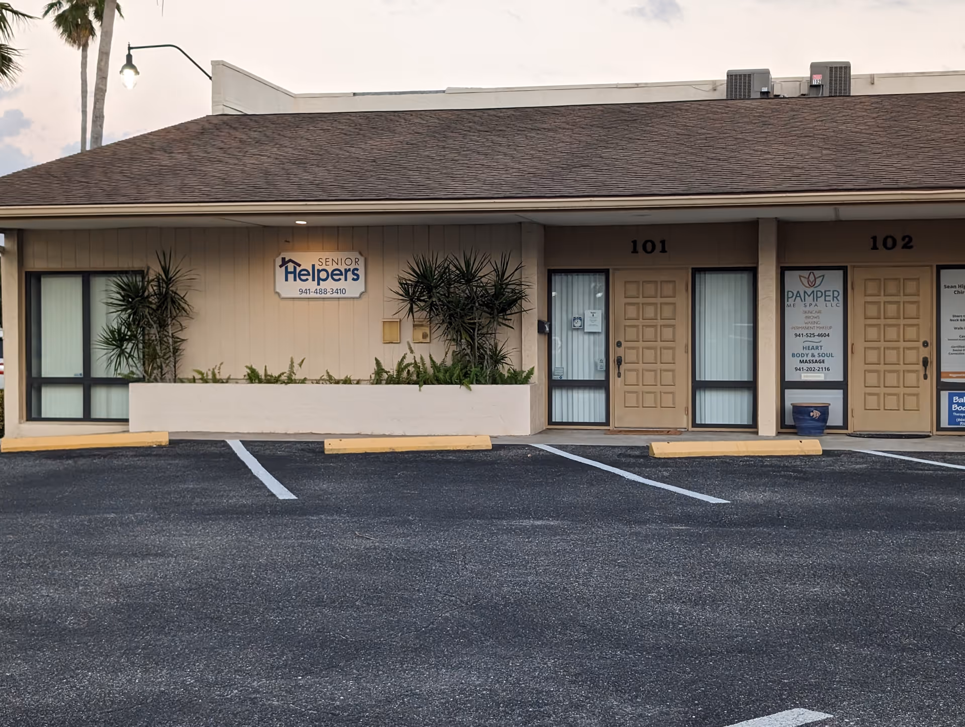 Exterior view of a Senior Helpers facility with numbered doors and a parking lot.