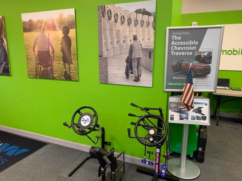Bright lime-green wall with wheelchair equipment and posters inside MobilityWorks showroom.