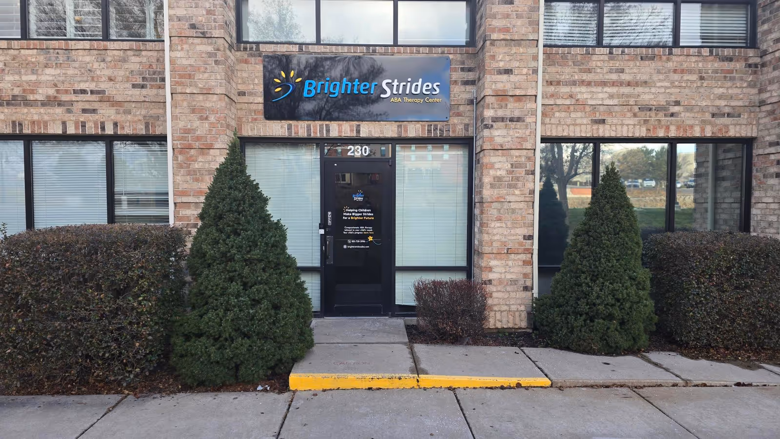 Brick building exterior with Brighter Strides ABA Therapy Center sign above a glass entrance.