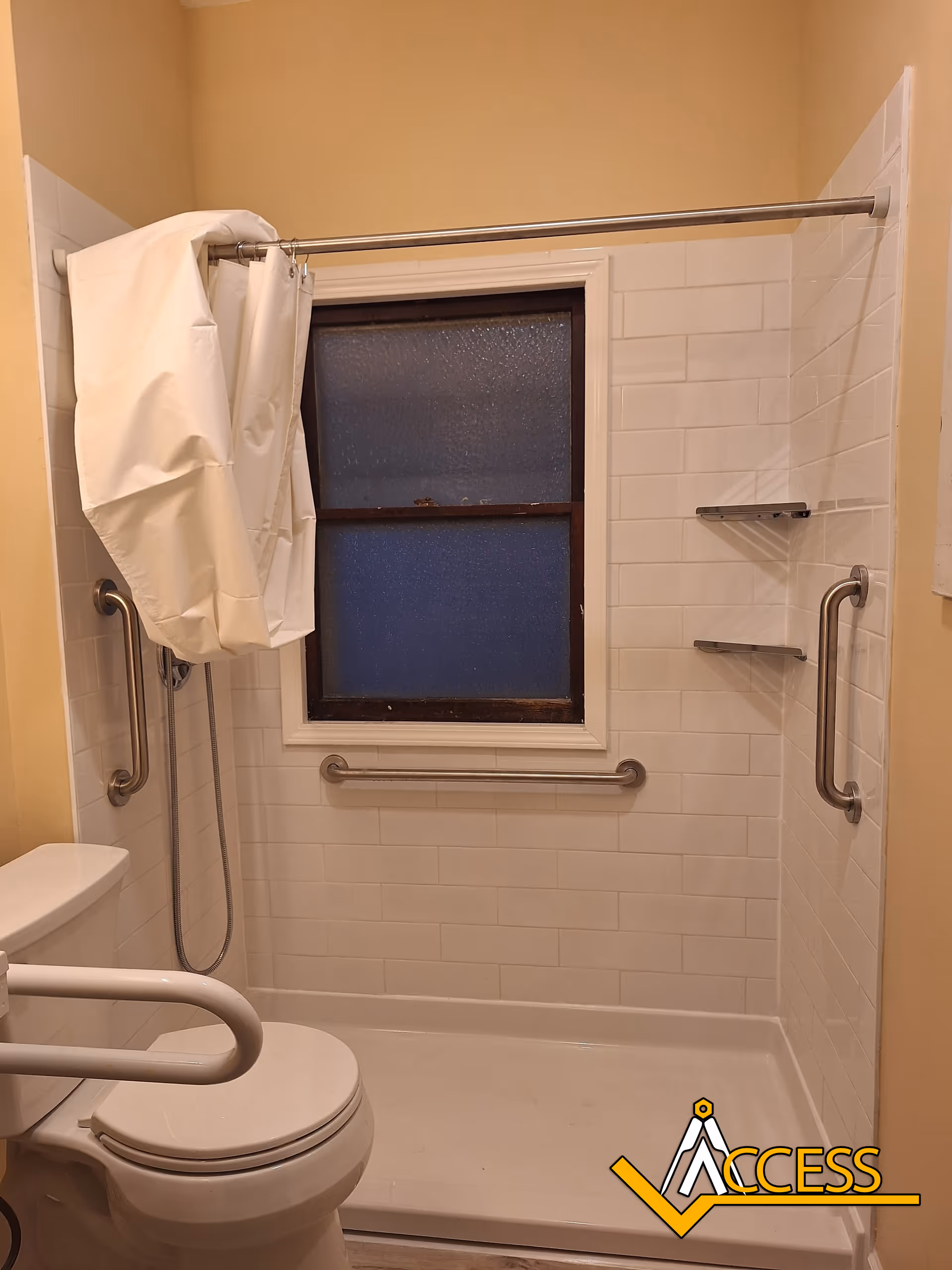 Accessible bathroom with a shower, grab bars, and a toilet in a senior living facility.