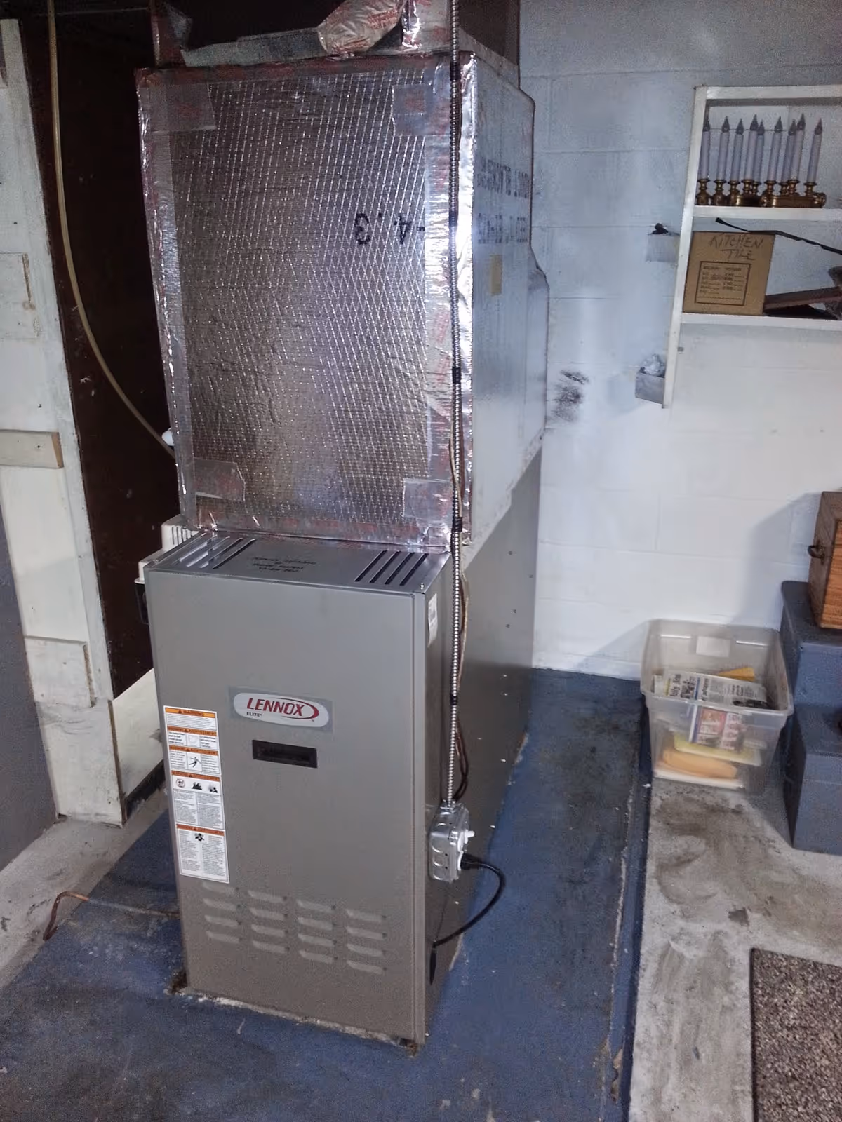 A Lennox furnace in a basement utility room with insulated ducts and wiring.