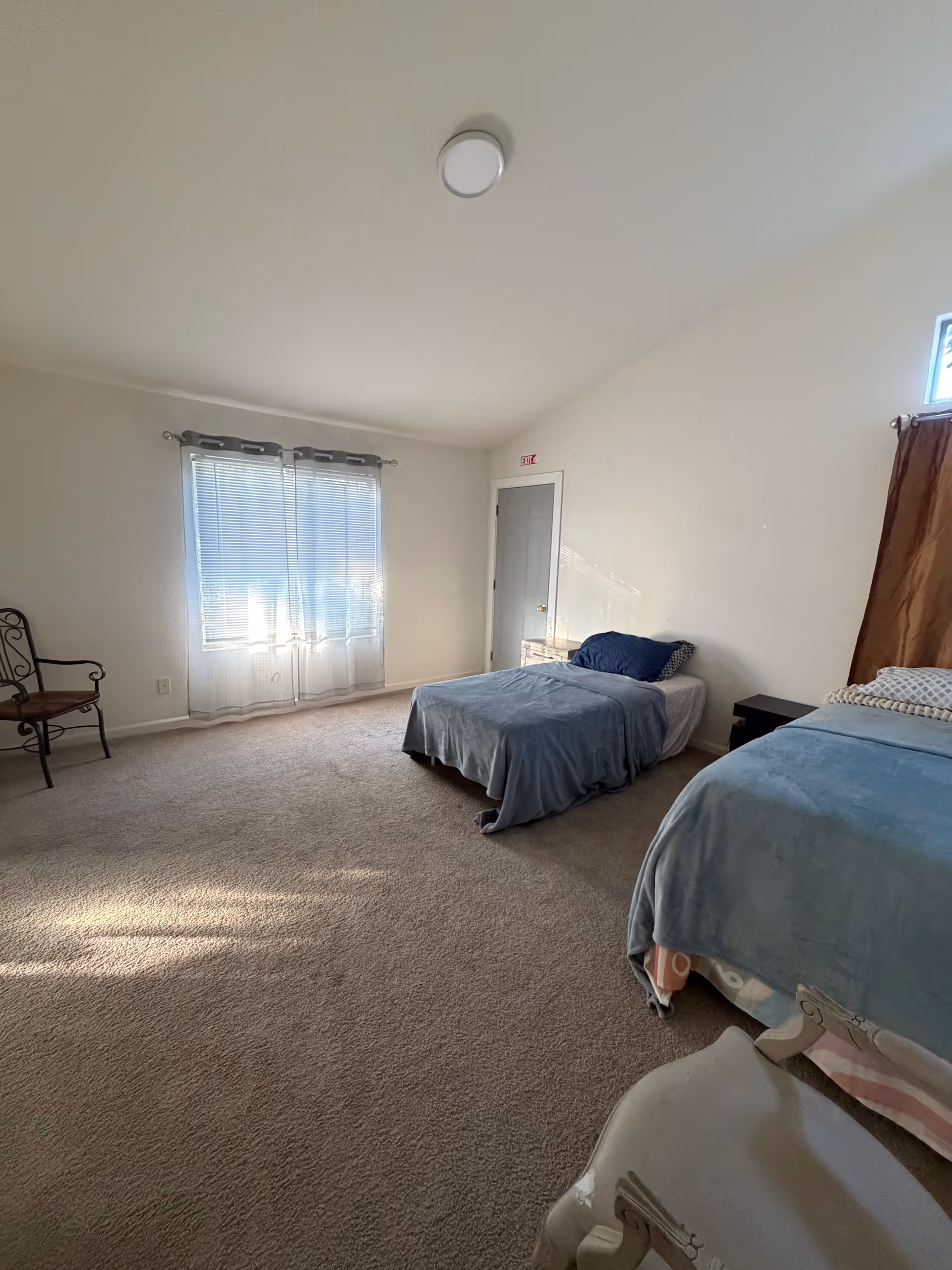 Bedroom in Salomee Home Care with two beds, chair, window, and nightstand.