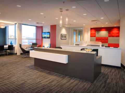 Modern facility lobby with a reception desk, seating areas, and large windows.