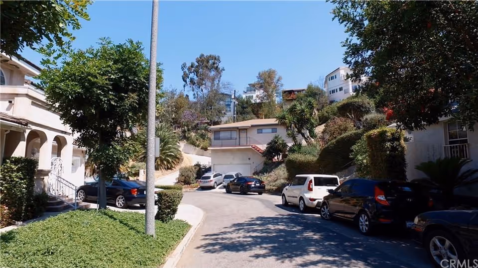 Outdoor street view of a hillside senior living area with parked cars.