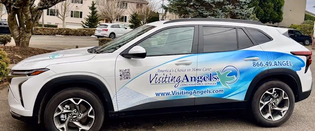 White SUV with Visiting Angels branding parked in a lot.