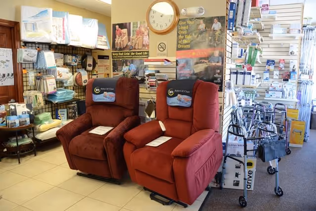 Two red recliner chairs in an indoor display area with medical supplies.