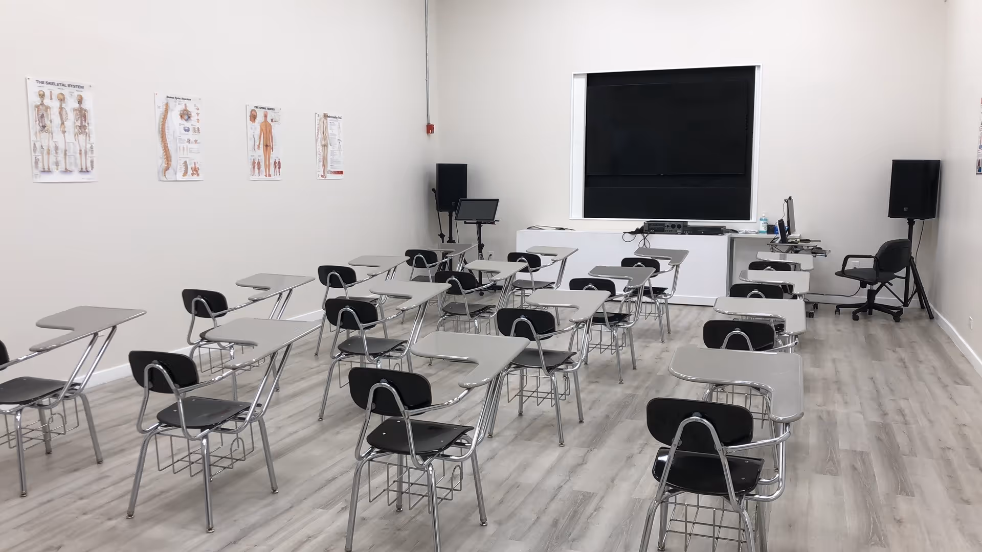Classroom-style training room with rows of desks and a large wall screen.