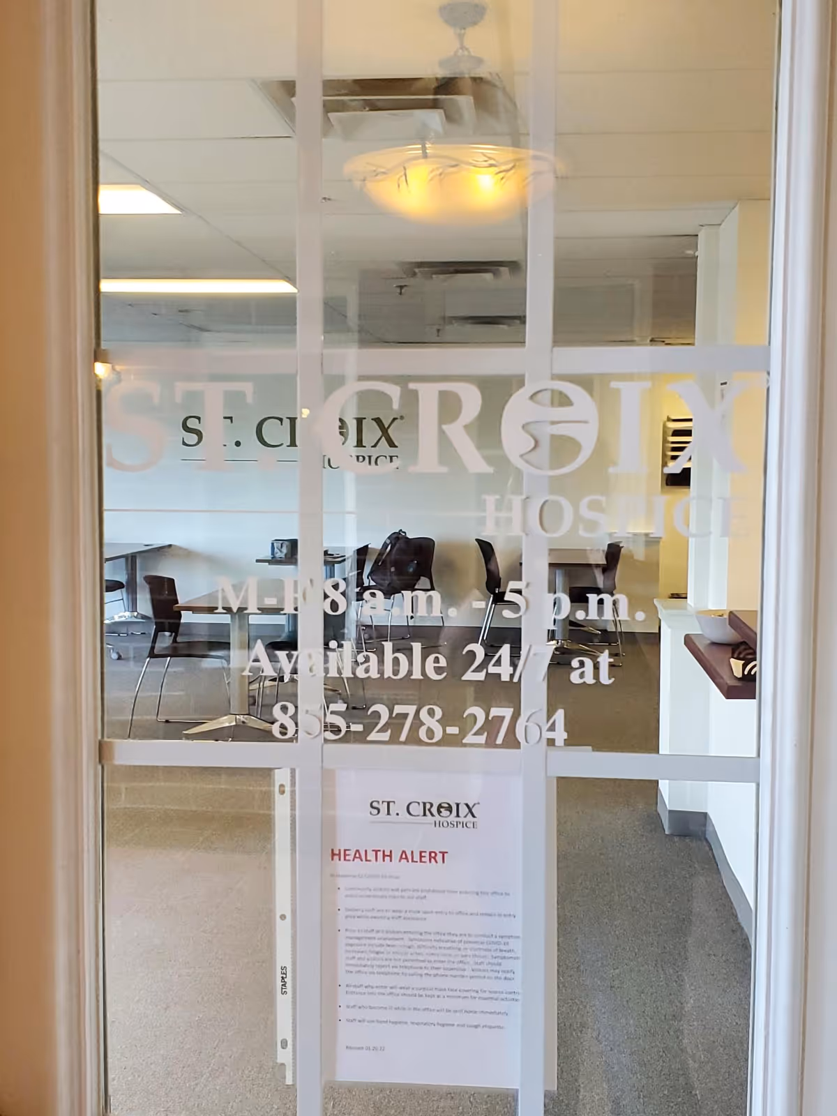 Glass door bearing St. Croix Hospice branding reveals seating area inside.