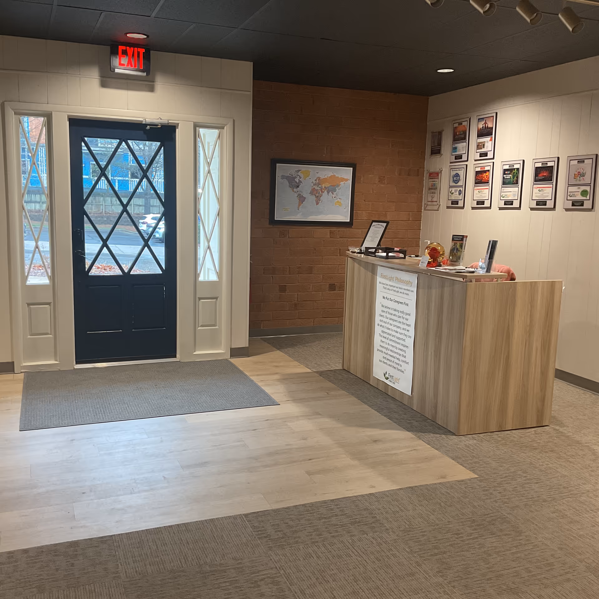 Interior lobby with reception desk, world map, and exit door.