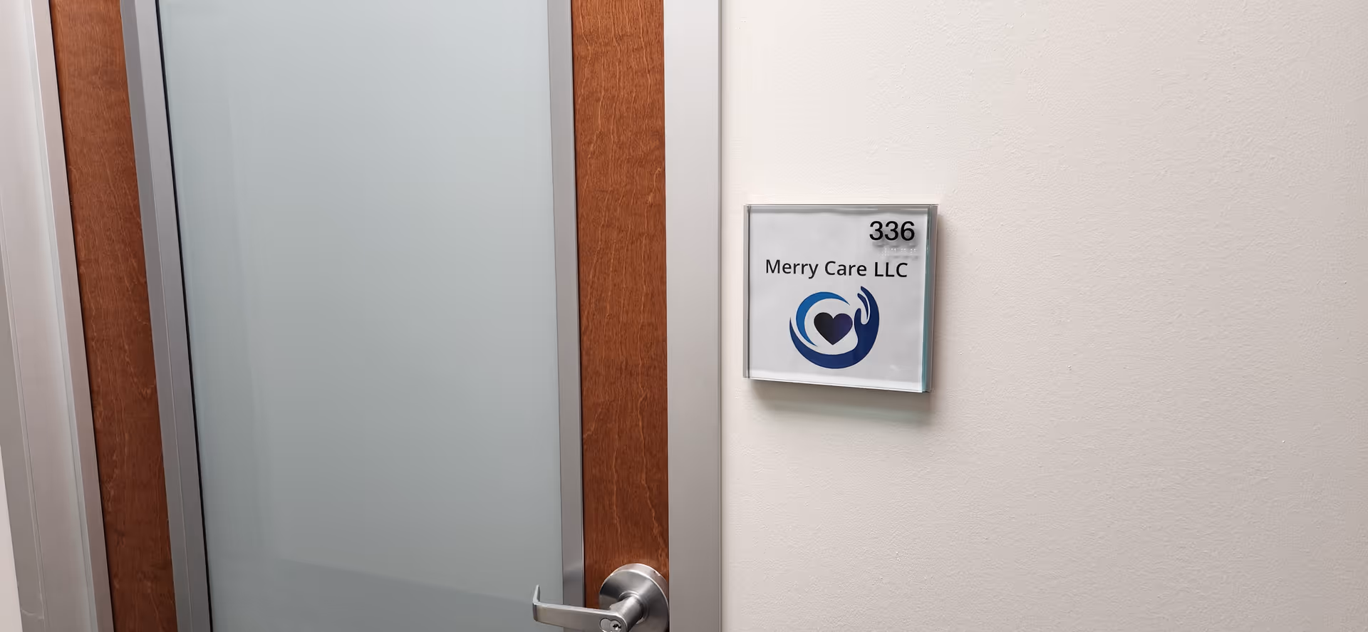 Interior door with frosted glass and a wall plaque reading 336 Merry Care LLC.