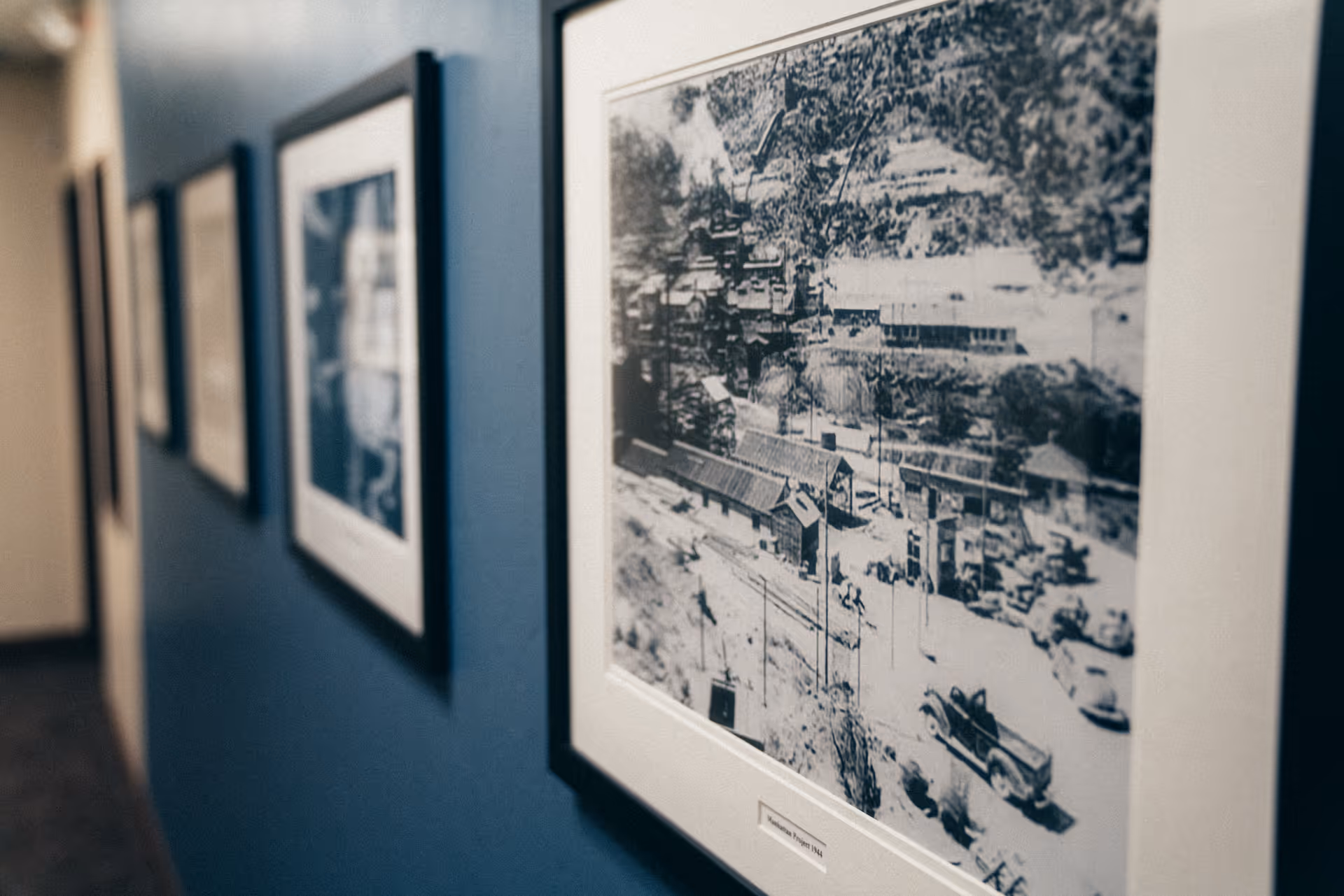 A wall in a hallway with multiple framed black-and-white photos hanging