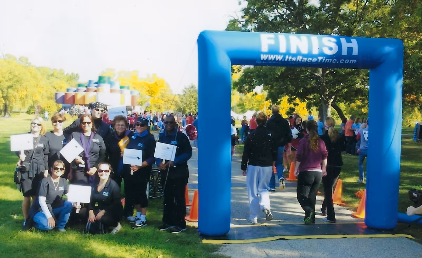 Outdoor park scene with a blue finish arch and group of people at a race event