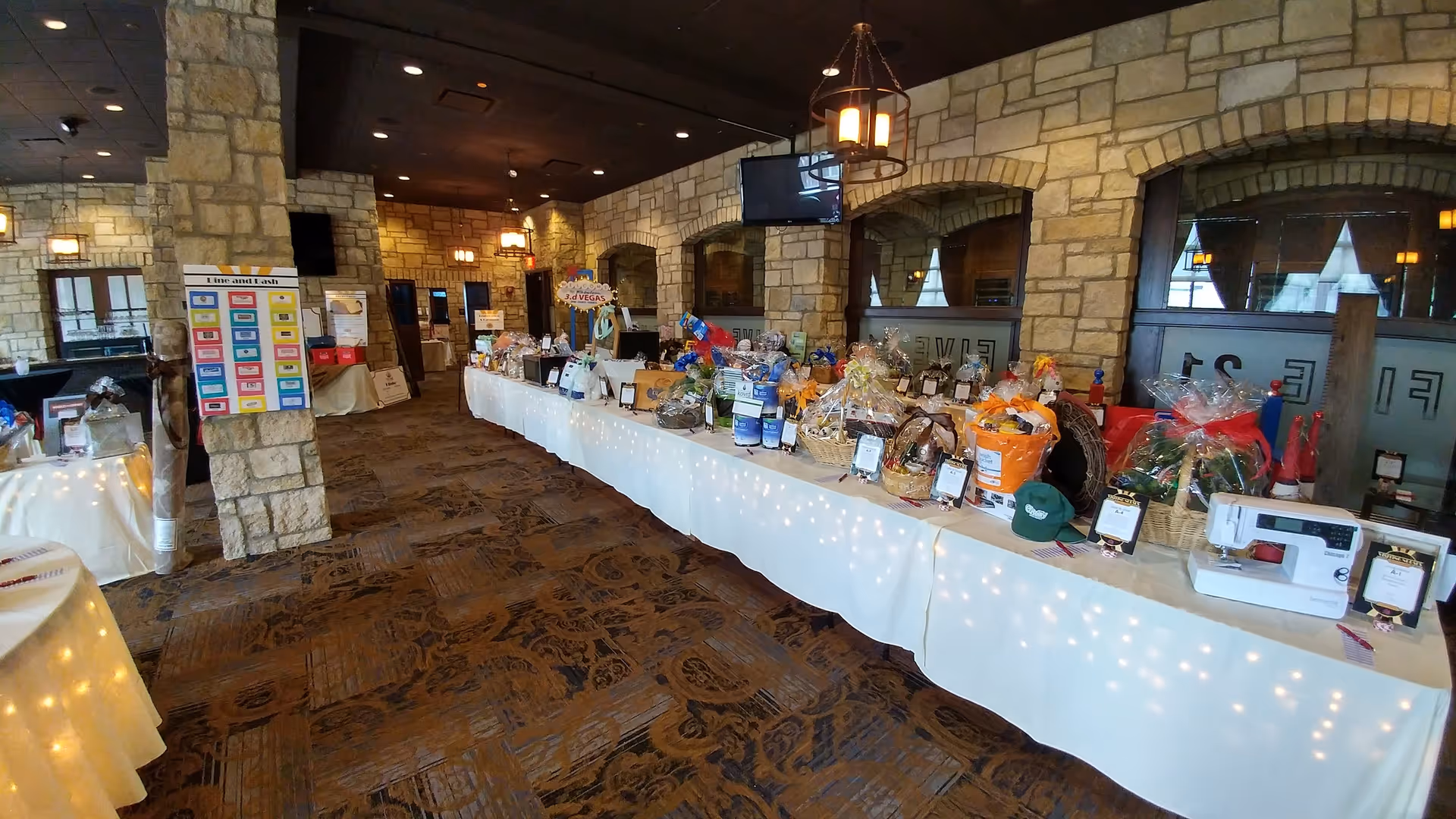 Stone-walled interior with a long table displaying gift baskets and prizes.