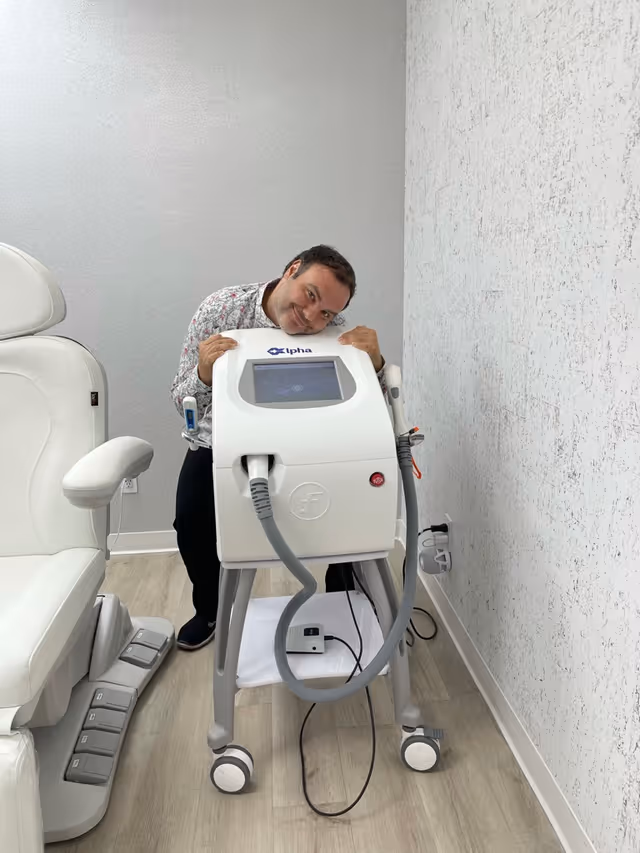 A man leans on a medical device in a clean, modern treatment room.