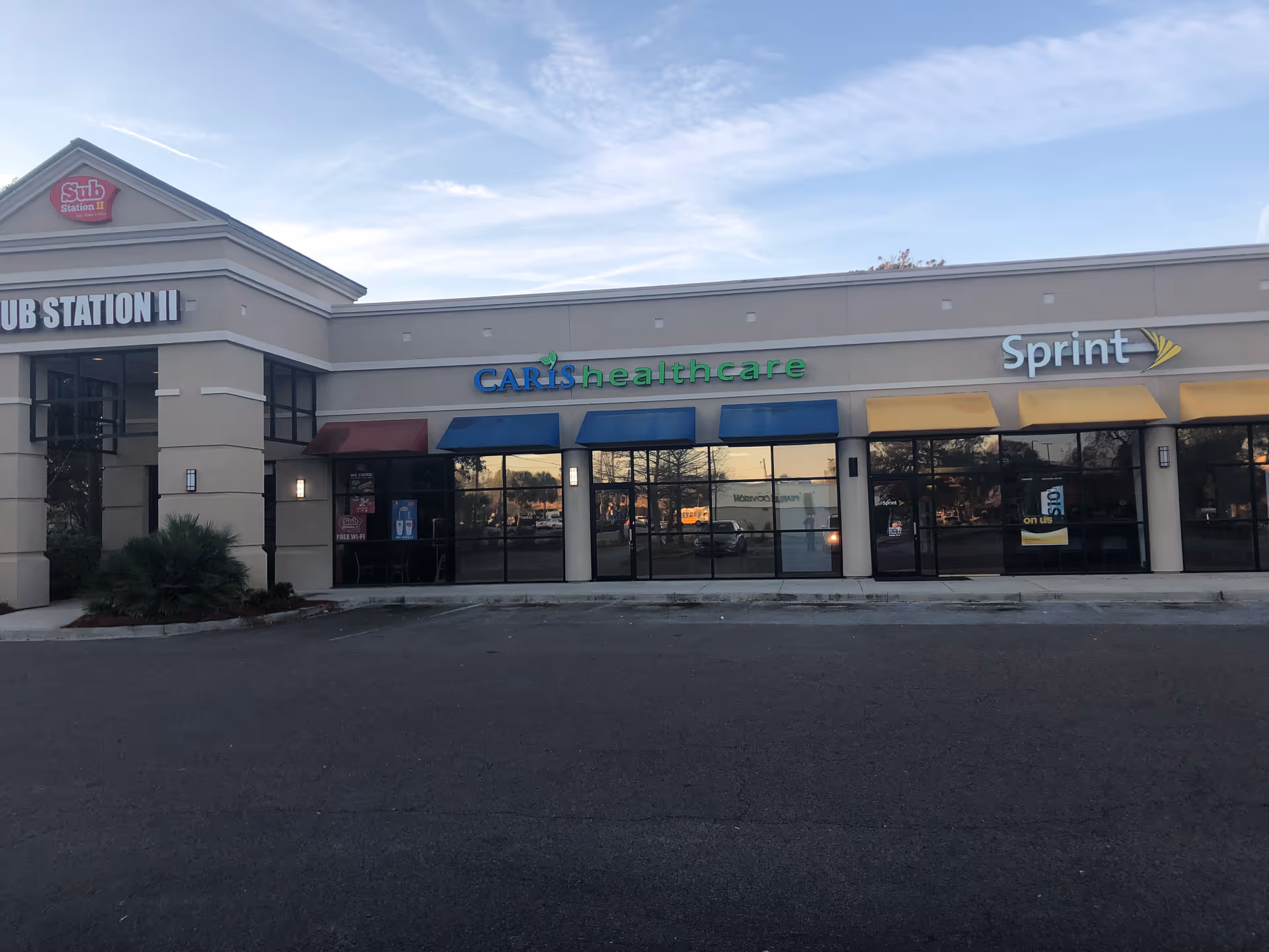 Exterior view of a strip mall storefront with Caris Healthcare center and Sprint on the right.