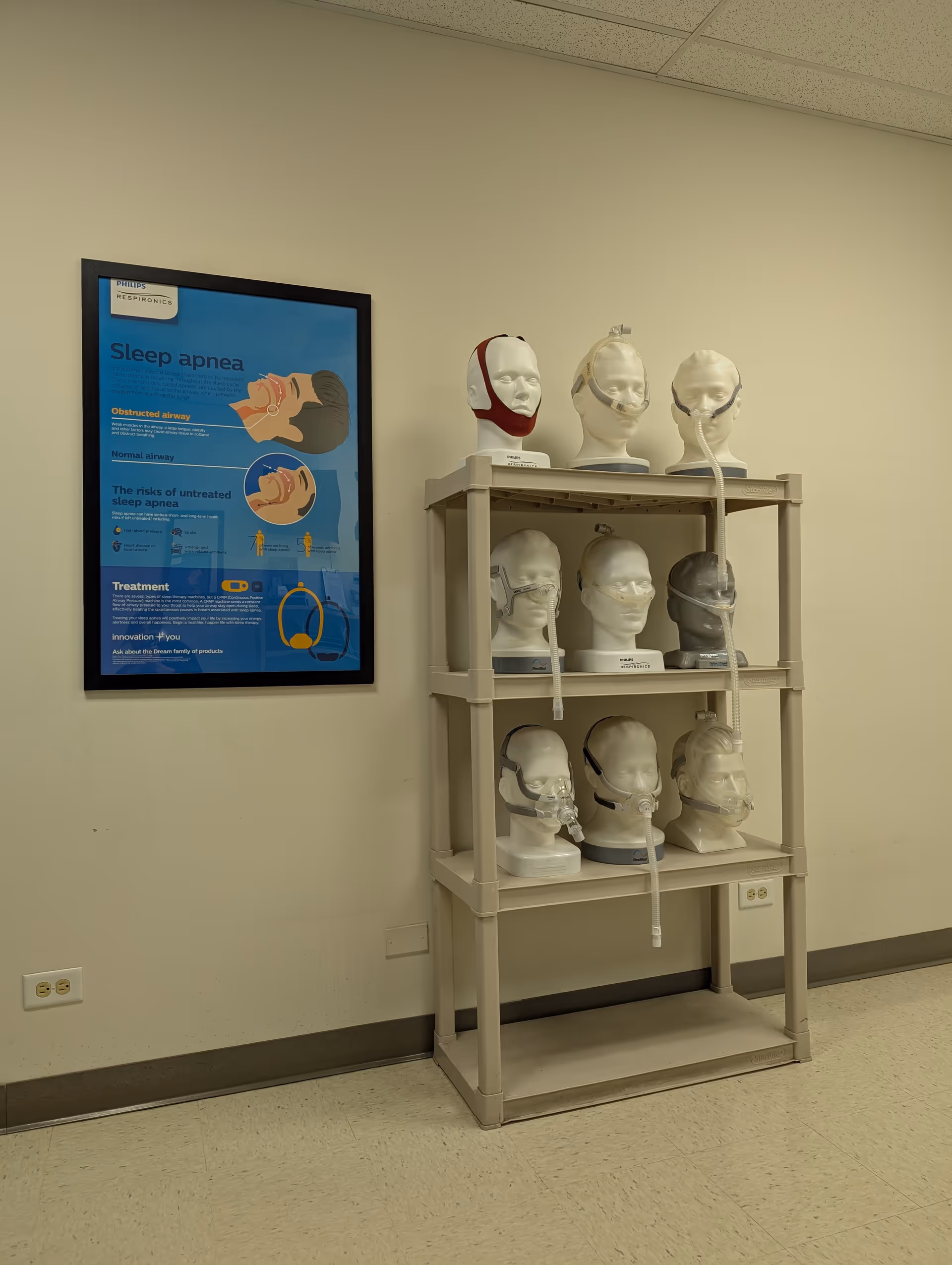 Medical display shelf with CPAP masks and a sleep apnea poster in a hallway.