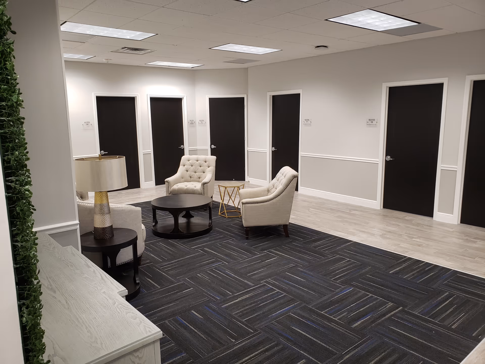 Neutral lobby area with cushioned chairs, coffee table, and multiple doors along walls.
