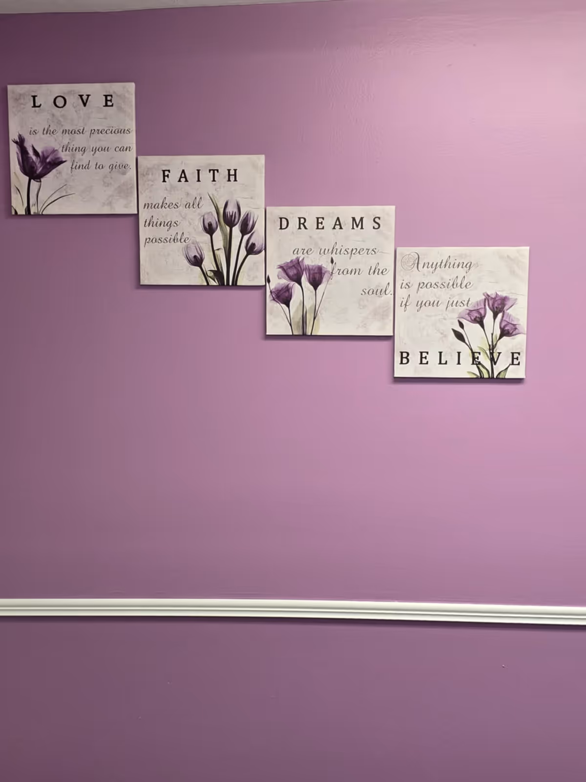 Purple wall with five-panel floral inspirational art displayed above a white molding.