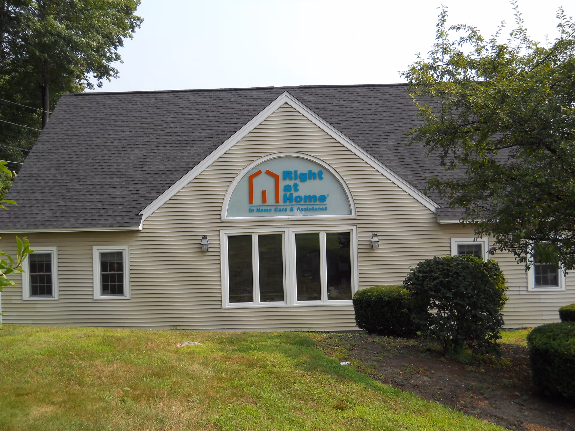 Exterior view of Right at Home facility with beige siding and arched sign